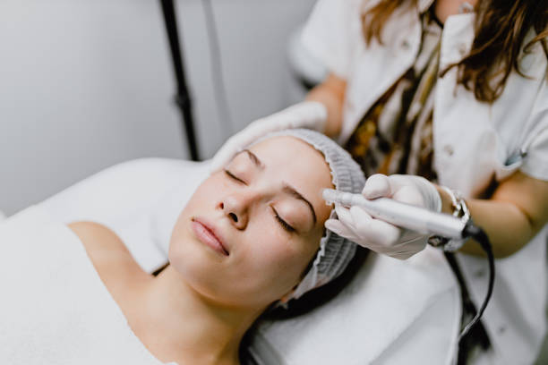 Beautiful young woman having a micro-needling collagen facial beauty treatment in the beauty clinic